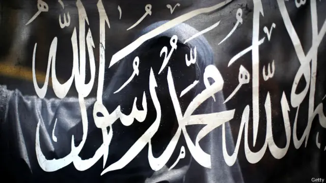 Una mujer detrás de una bandera en apoyo a Estado Islámico