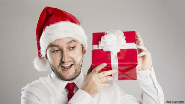 Un ejecutivo con sombrero de Papá Noel y una caja de regalos