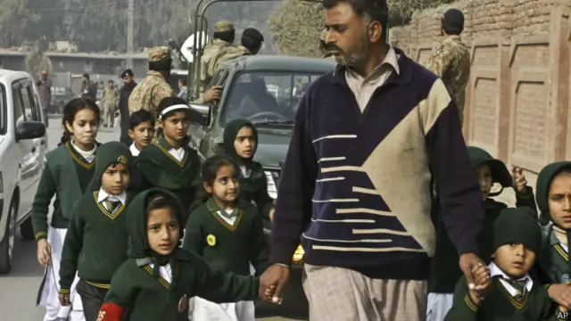 पेशावर के एक स्कूल से बच्चों को निकलते एक सुरक्षाकर्मी