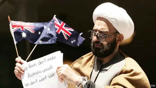 محمد حسن منطقی پس از پناهندگی به استرالیا در لباس روحانیون شیعه به فعالیت علیه "جنگ با مسلمانان" پرداخت