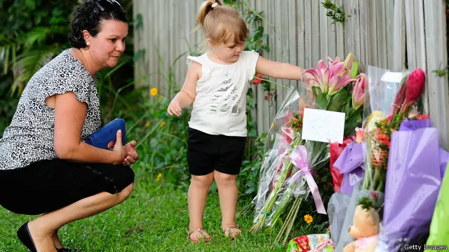 امرأة وابنتها تضعان باقة من الورد قريبا من المنزل الذي عثر فيه على الأطفال القتلى.