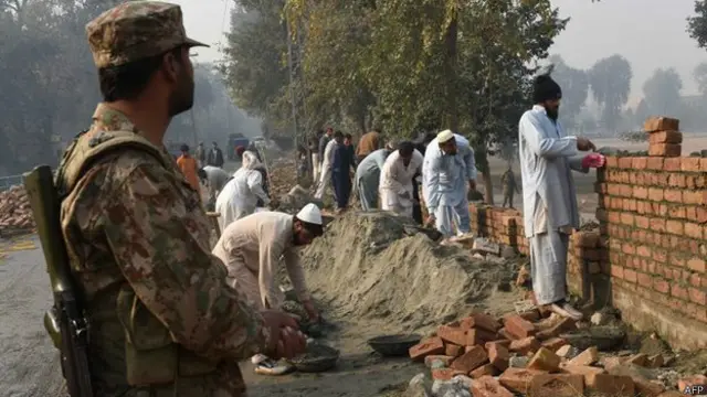 قام عمال باكستانيون بإعادة بناء جدار المدرسة التي تعرضت للهجوم. 