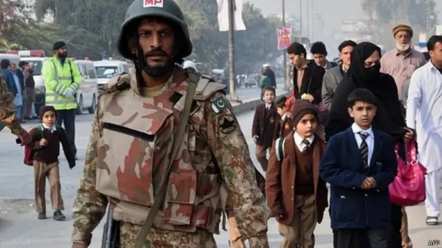 تلاميذ يسيرون إلى جانب جندي بعد مذبحة بيشاور