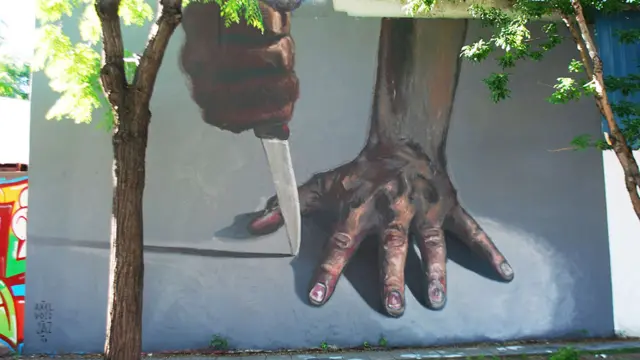 Mural del grafitero argentino JAZ, se ve una mano y un cuchillo