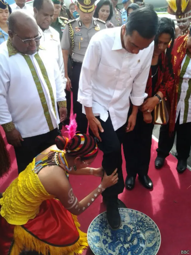 Presiden Jokowi menjalani tradisi 'injak piring' saat baru tiba di Bandara Sentani, Papua.