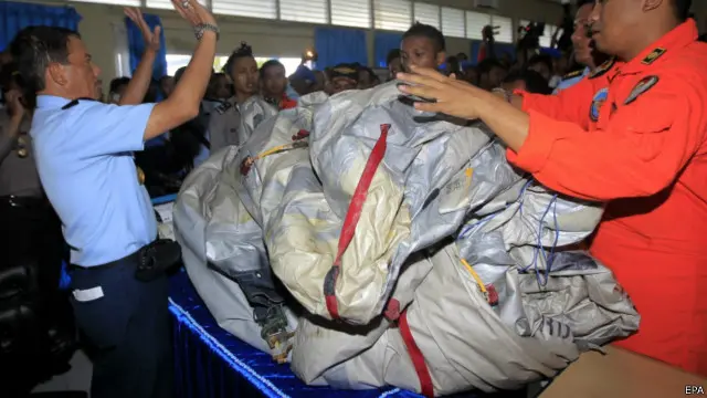 印尼空军人员检视一张怀疑是飞机充气紧急逃生筏的塑料