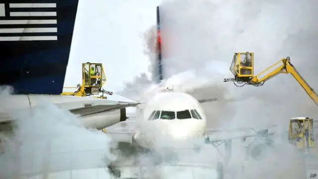 विमान पर लगी बर्फ हटाती मशीनें