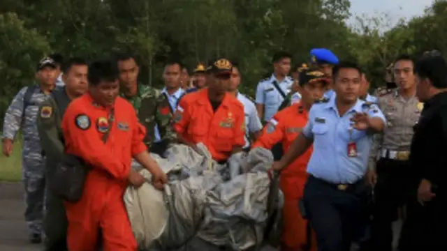 एयर एशिया के लापता विमान के मलबे को ले जाते इंडोनेशियाई अधिकारी