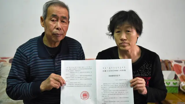呼格吉勒图父母李三仁、尚爱云展示内蒙古高院的国家赔偿决定书（新华社图片31/12/2014）