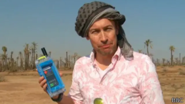 Periodista de la BBC con una carcasa satelital en un desierto de Marruecos