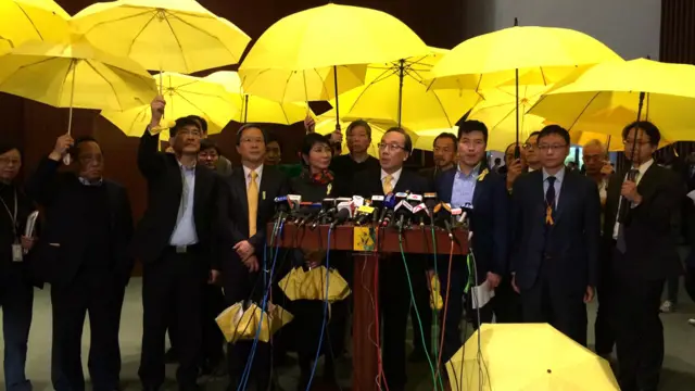 香港泛民主派议员在立法会会议大厅外举起黄色雨伞抗议（BBC中文网图片7/1/2015）