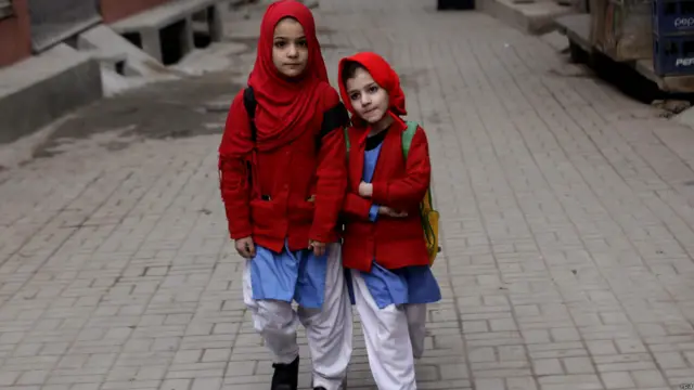 Dua murid sekolah berpose dalam perjalanan pulang ke rumah mereka.