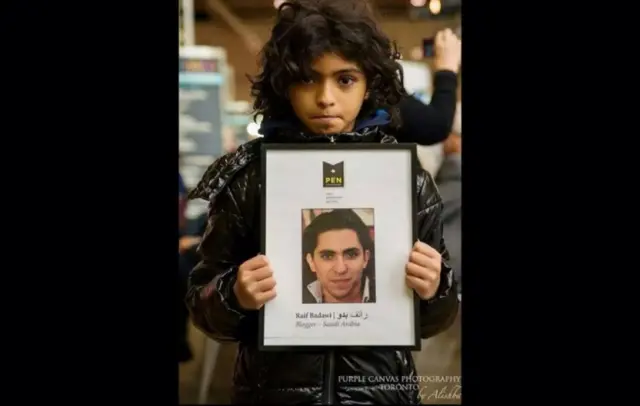 ابن بدوي يحمل ملصقا للمطالبة بالافراج عن والده