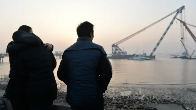 落水船员家属在岸边等待消息。