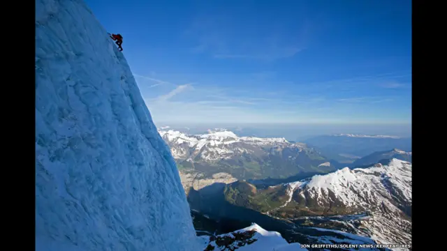 Un escalador en la empinada ladera de una montaña.