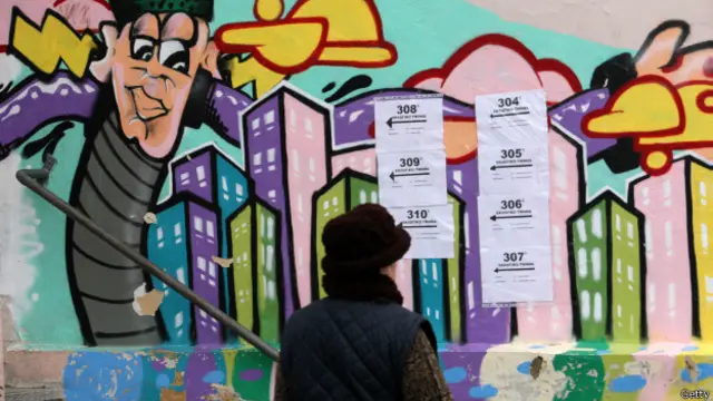 Женщина на фоне объявлений об участках для голосования