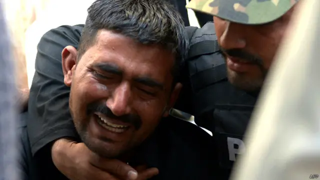 कराची में एक पुलिसकर्मी अपने साथी की मौत पर रोता हुआ