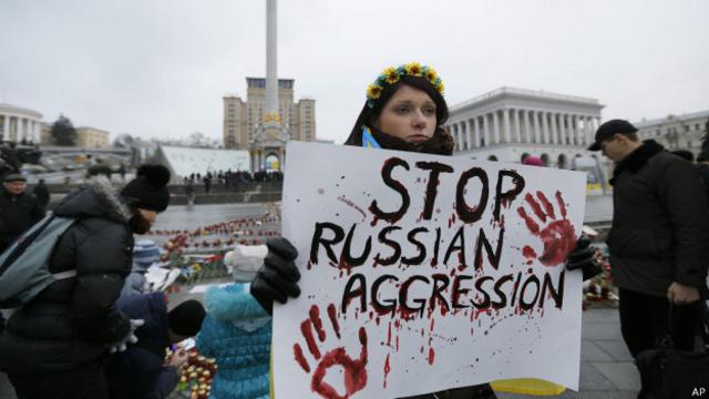 Женщина в Киеве с плакатом "Остановите российскую агрессию"