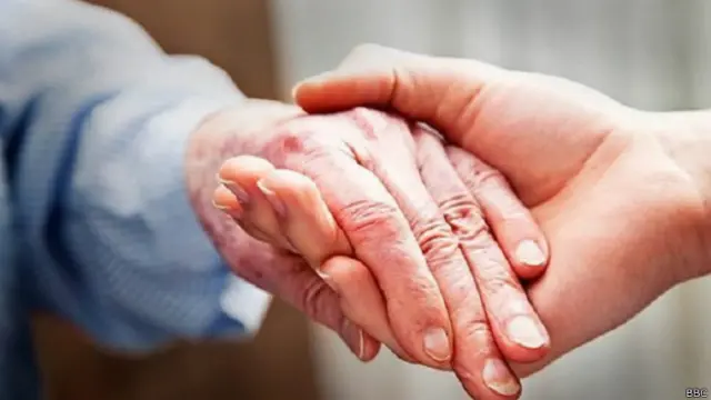 बुजुर्ग व्यक्ति का हाथ थामे एक नौजवान 