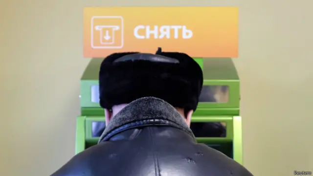 Человек перед банкоматом в отделении Сбербанка