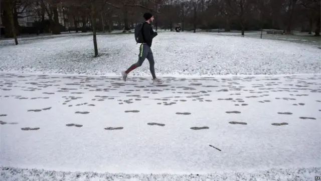 لندن کے سینٹ جیمز پارک میں ایک شخص برف باری کے باوجود جاگنگ کرتے ہوئے۔