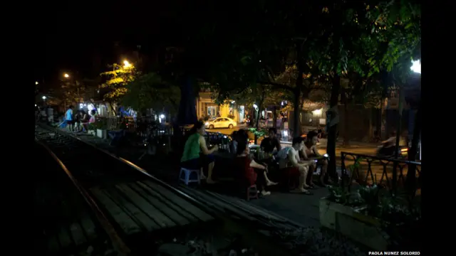 Orang duduk di samping rel di malam hari.