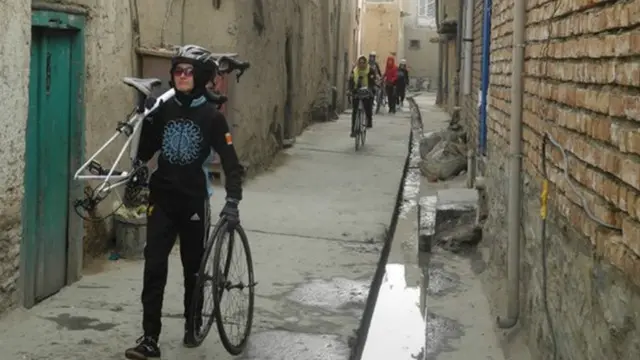 خواتین اپنی سائیکلیں اٹھا کر افغانستان کے واحد پیشہ ور سائیکلنگ کھلاڑی عبدل صادق کے مکان سے نکل کر ایک کچی گلی میں کھلی نالیوں کے پاس سے ہوتی ہوئی گزرتی ہیں