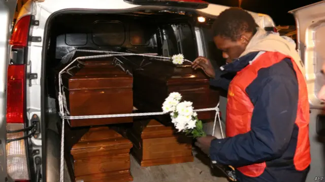 İtalya'da denizden çıkarılan göçmenlerin tabutlarına bir kişi çiçek bırakıyor. 