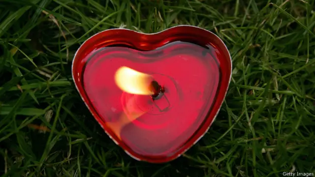 Красная свеча в форме сердца на траве