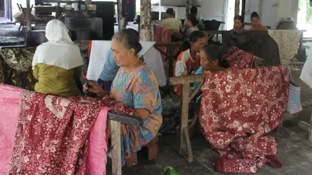 Para pengrajin batik di pabrik Sekar Kencana tengah menyelesaikan batik tulis. 