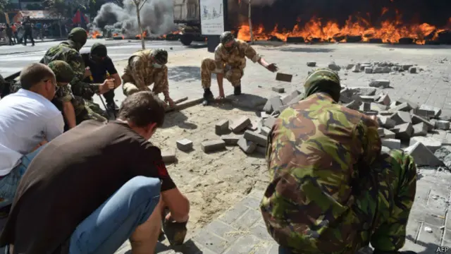 Молодые люди выковыривают из мостовой булыжники