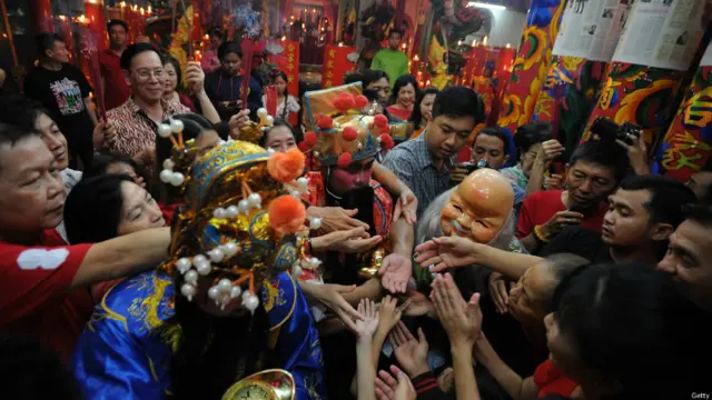 在印尼，一座庙宇中的“财神爷”给前来祈福的客人派发“元宝”