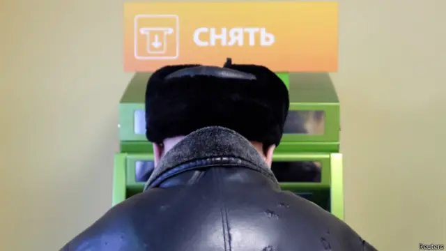 Мужчина снимают деньги в банкомате