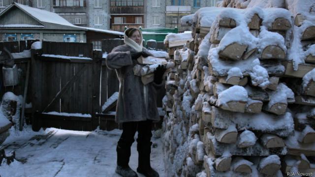 Жительница частного дома в городе Тара Омской области берет дрова из поленницы.  12 декабря 2012 г.