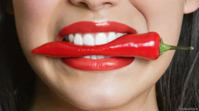 Mujer con un chile en la boca