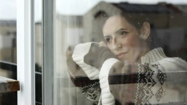 Una mujer hermosa mira a través de una ventana