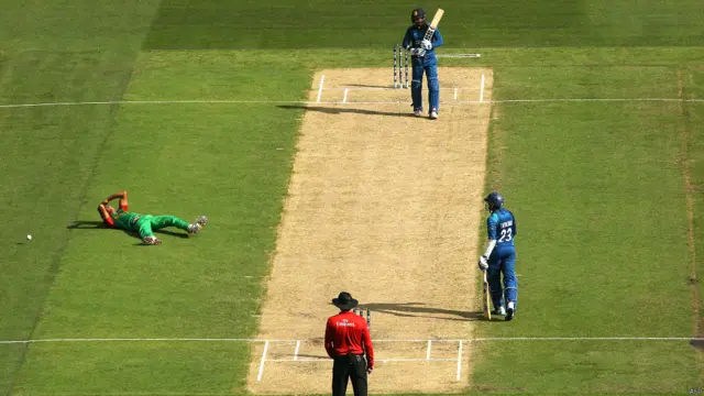 بنگلہ دیش کے بولر تسکین احمد اپنی ہی گیند پر کیچ نہ پکڑ سکنے کے بعد گراؤنڈ پر لیٹے ہوئے ہیں۔ 