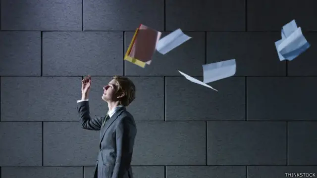 Una persona lanza al aire una carpeta con papeles