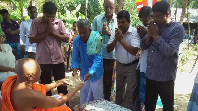 Mudiyanselage (de azul, à esquerda) assina documentos para entrega da terra a templo budista