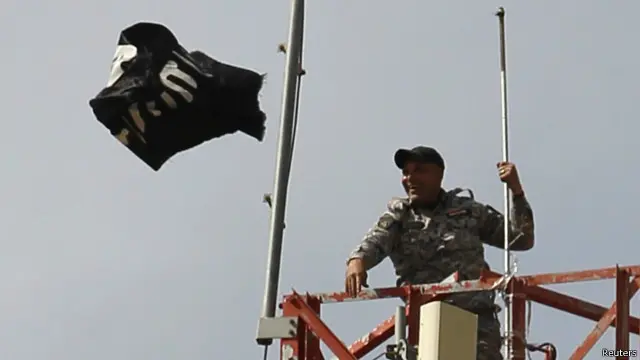 جندي عراقي يلقي بعلم تنظيم الدولة الإسلامية من فوق برج في ناحية العلم شمال تكريت. 
