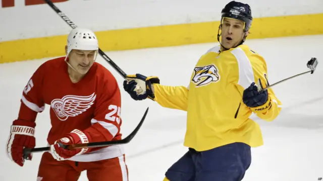 Stu Grimson, memegang tongsis saat timnya bertanding di pertandingan khusus alumni pemain hoki profesional di Nashville, Tennesse, Amerika Serikat.