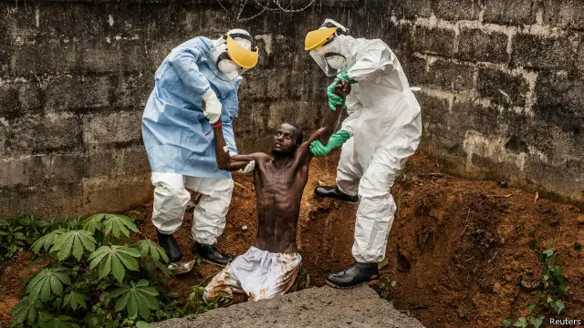 موظفو الإغاثة الصحيون يحاولون يساعدون رجل سيراليوني مصاب بالفيروس على النهوض لنقله إلى مركز للعلاج خارج العاصمة فريتاون.