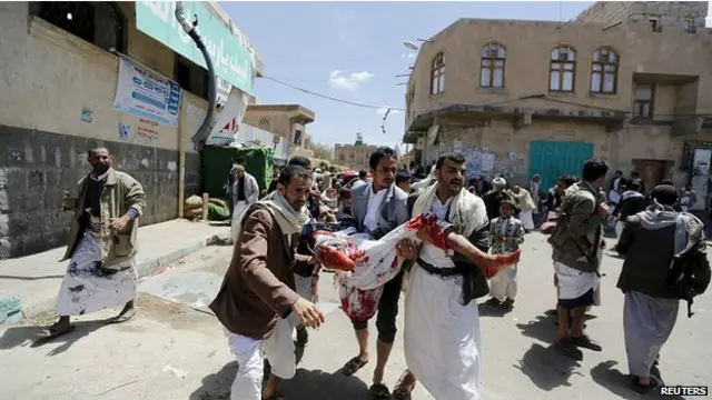 志願者用沾滿血跡的被單將受害者抬走。