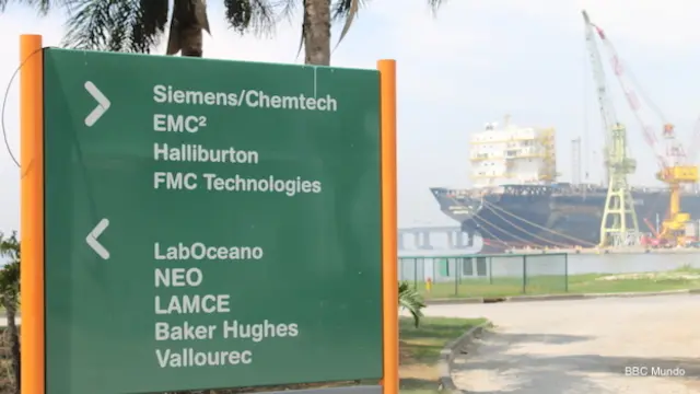 Delante de un barco petrolero, un cartel indica cómo llegar a diferentes empresas del parque tecnológico de la Universidad Federal de Río de Janeiro.