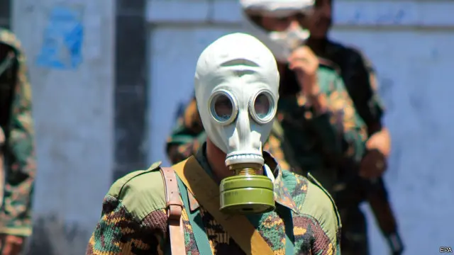 فرد من الجيش اليمني مؤيد للحوثيون يرتدي قناع غاز خلال مواجهة مع مظاهرة مناهضة للحوثيين في مدينة تعز.