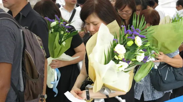 一名女士手持花束排队(BBC中文网图片26/3/2015)