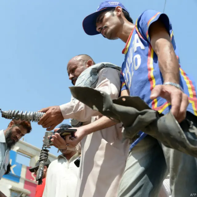 دھماکے کے بعد اہلکار جائے وقوع سے تباہ شدہ موٹر سائیکل کے حصے اور دیگر شواہد جمع کرتے دکھائی دیے