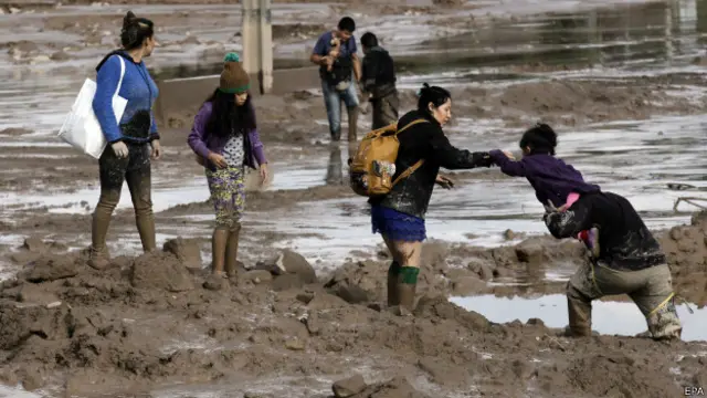 Un grupo de gente cruza una calle inundada