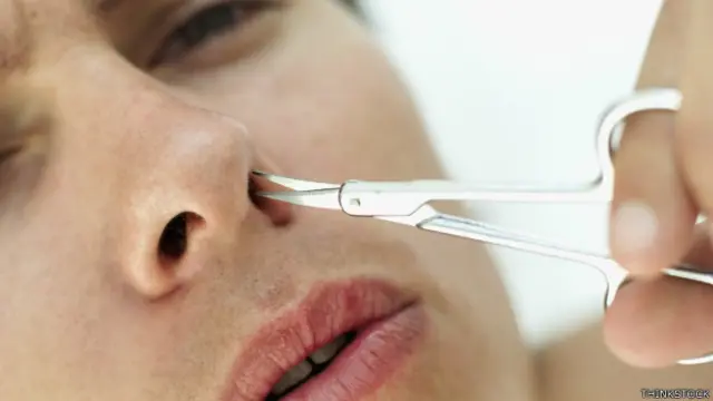 Joven cortándose los pelos de la nariz.