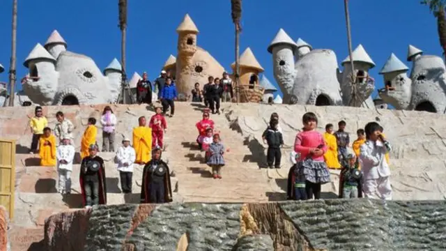 Pengunjung taman hiburan disambut para penari yang tinggal di jamur raksasa.